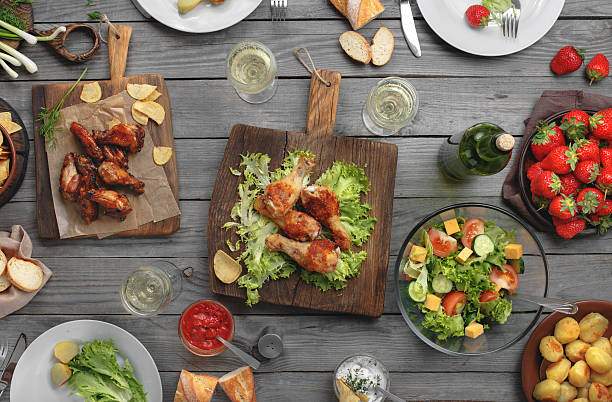 Different food cooked on the grill Different food cooked on the grill on a wooden table, grilled chicken legs, buffalo wings, salad, potatoes, bottle of wine and three glasses of wine and strawberry, top view. Outdoors Food Concept buffalo iowa stock pictures, royalty-free photos & images