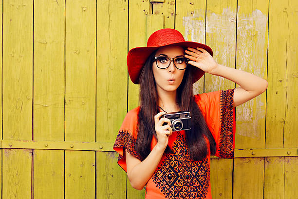 ragazza divertente con fotocamera retrò e cappello da sole rosso - indiscreet foto e immagini stock