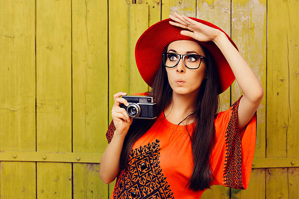 ragazza divertente con fotocamera retrò e cappello da sole rosso - indiscreet foto e immagini stock