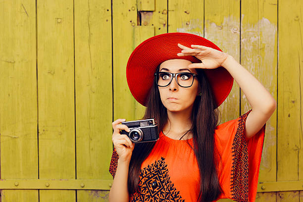 ragazza divertente con fotocamera retrò e cappello da sole rosso - indiscreet foto e immagini stock