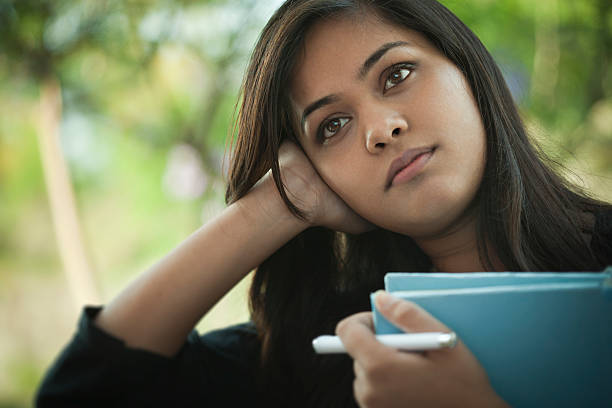 istock Late teen Asian girl student thinking while holding a book. 545262812