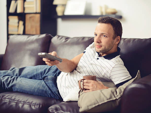 istock Young, handsome man in home interior watching TV 545263738