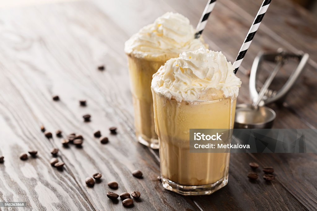 Iced coffee with ice cream Iced coffee with whipped milk and caramel ice cream in tall glasses on rustic wooden table, selective focus Backgrounds Stock Photo