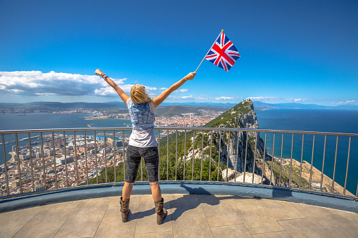 Woman enjoy with the British flag in hand on top of Gibraltar Rock. Gibraltar is a territory of South West Europe Which is part of the United Kingdom.
