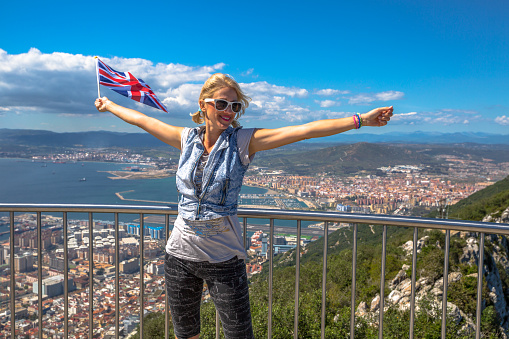 Woman enjoy with the British flag in hand on top of Gibraltar Rock. Gibraltar is a territory of South West Europe Which is part of the United Kingdom.