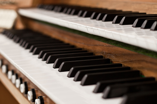 Bright white Piano keys on old musical instrument with high tone ebony and ivory close up panoramic