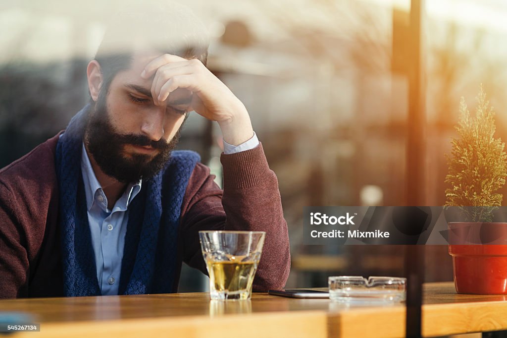 Everyday stress Depressed male drinking alcohol in a bar during daytime Alcohol Abuse Stock Photo