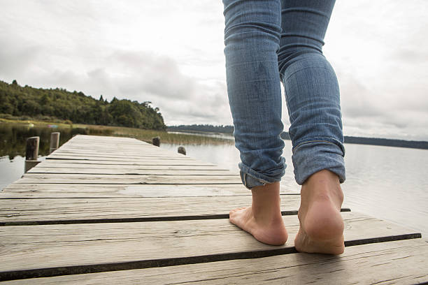 istock Close up on woman's feet standing on jetty above lake 545271060