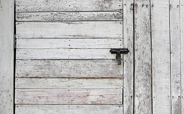 istock Old wooden plank vertical and horizontal door with padlock 545272578