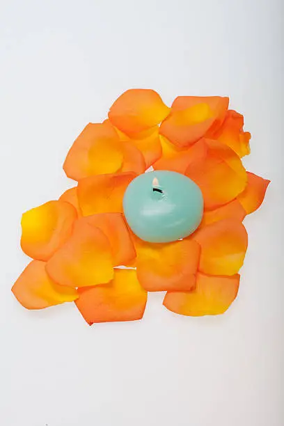 Spilt petals of the orange-rose around the aromatic candle