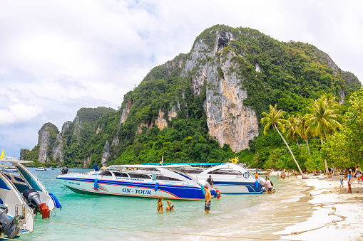 Krabi, Thailand - July 29, 2014: Speed boats and drivers waiting for tourists on the beach. Beach of Koh Phi Phi Don. Phi-Phi island, Krabi Province, Thailand.  Phi Phi is one of the most visited island in Thailand. The islands feature beaches and clear water that have had their natural beauty protected by national park status