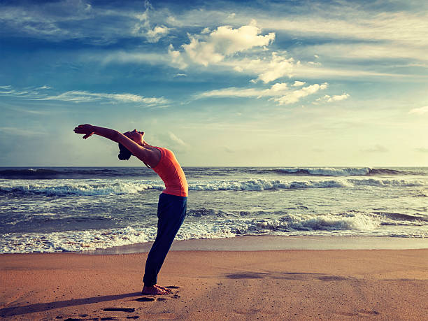 jeune femme en bonne forme sportive faisant du yoga surya namaskar la salutation au soleil - salutation au soleil photos et images de collection