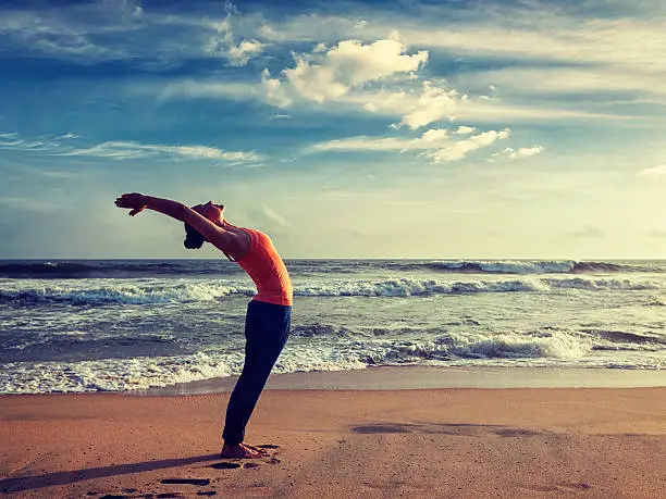 Photo of Young sporty fit woman doing yoga Sun salutation Surya Namaskar