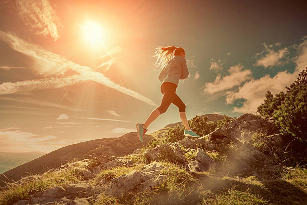 Female running in mountains under sunlight.