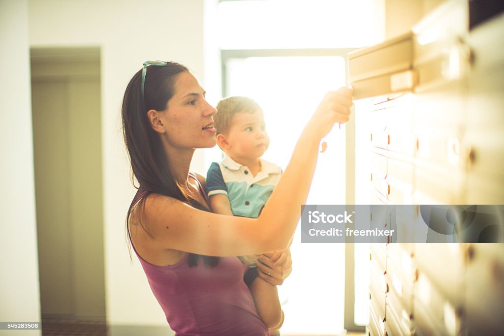 Who's got mail Woman carrying a baby boy while they look i they got some mail in the mailbox Mailbox Stock Photo