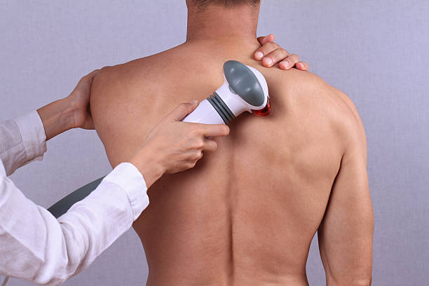 Therapist doing healing infrared treatment on man's back . stock photo
