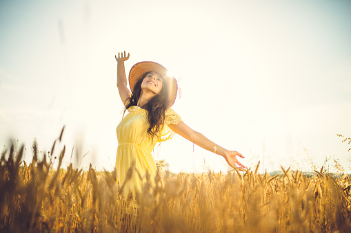 happy young woman with open arms in the wheat field ona a sunny day
