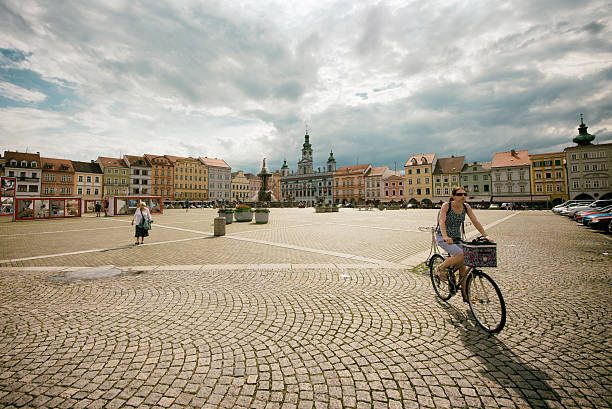 view of the historic town hall and surrounding buildings on Přemysl Otakar II  square in České Budějovice, Czech Republic. The town hall is a prominent building with a clock tower and ornate facade, dominating the square. The surrounding buildings feature colorful facades and architectural details, showcasing the town's rich history.