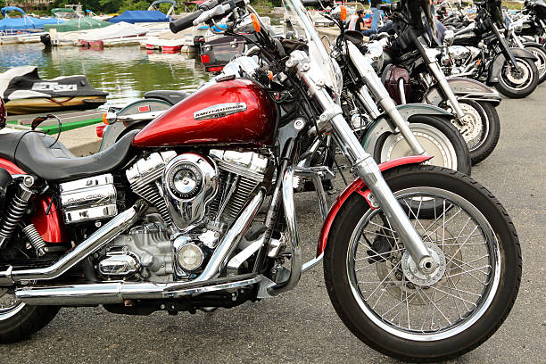 Greenwood Lake New York, USA - June 26, 2016: Harley Davidson Super Glide parked first in a row of Harleys with small boats in the background,  lakeside at this biker handout. Adult toys abound at this location.