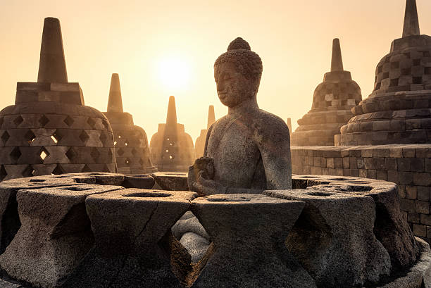Buddha statue with sunshine through pagodas at Borobudur, Indonesia