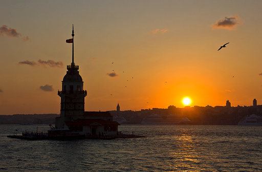 Istanbul, Turkey - August 11, 2013: Sunset with Maiden's Tower in Istanbul, It's one of the symbols of Turkey and there is a part of the Bosphorus at the background with people. Some of people visits the restaurant in tower