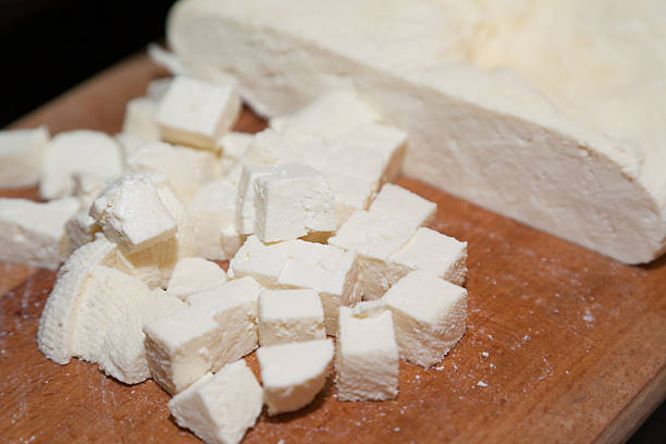 paneer cut into pieces on cutting board stock photo