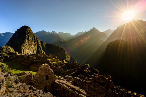 Sun rising over the mountains at the Inca ruins of the city of Machu Picchu, Peru. Sun is striking the Wayna Picchu mountain that overlooks the city.