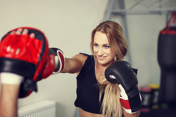 Woman boxer preparing in gym with instructor Happy woman boxer preparing in gym with instructor blonde female bodybuilders stock pictures, royalty-free photos & images