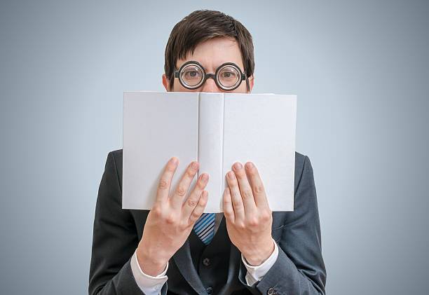 istock Young man is reading and hiding his face behind book. 545355102