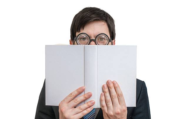 istock Young man is reading and hiding his face behind book. 545355134