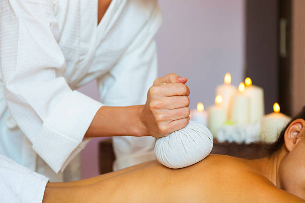 linda jovem mulher fazendo massagem nas costas com bolsa de arroz - herbal compress balls - fotografias e filmes do acervo