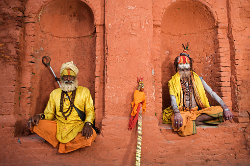 Sadhu - indian holymen sitting in the temple. In Hinduism, sadhu, or shadhu is a common term for a mystic, an ascetic, practitioner of yoga (yogi) and/or wandering monks. The sadhu is solely dedicated to achieving the fourth and final Hindu goal of life, moksha (liberation), through meditation and contemplation of Brahman. Sadhus often wear ochre-colored clothing, symbolizing renunciation.http://bhphoto.pl/IS/nepal_380.jpg
