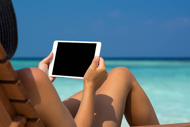 istock Blank empty tablet computer in hands of women on  beach 545358496