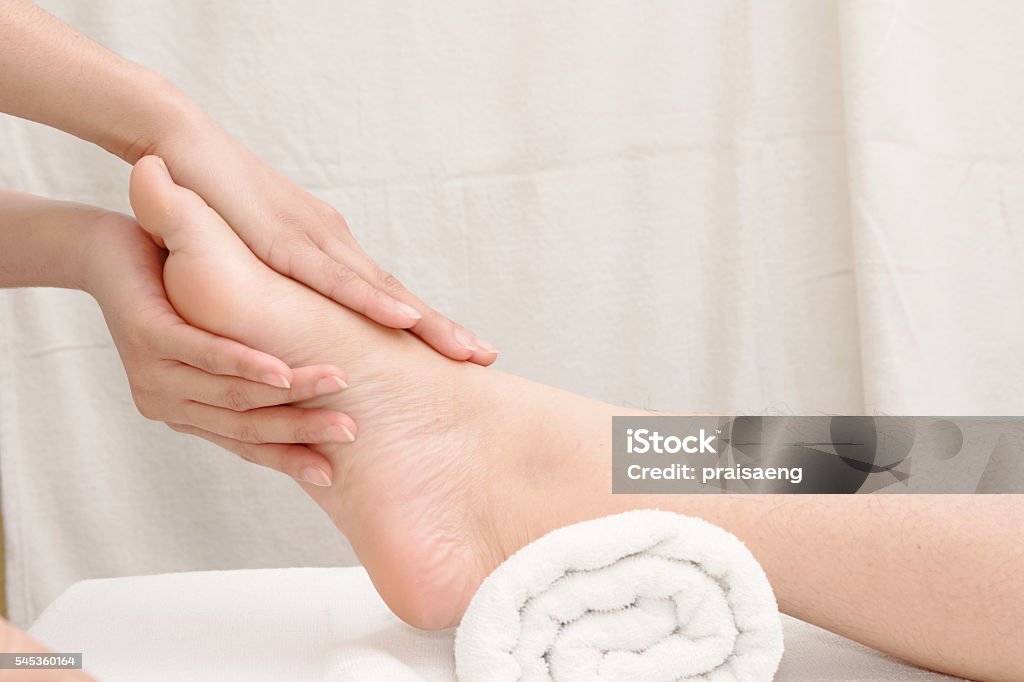 Foot massage, therapist's hands massaging female foot Adult Stock Photo
