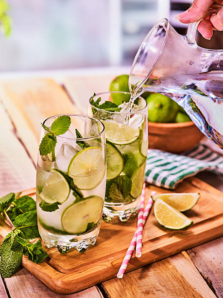 istock Hand is pouring from jug of mohito cocktail drink 545360416