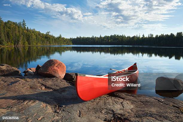 Foto de Canoa Vermelha Na Costa Rochosa Do Calmo Lago Norte e mais fotos de stock de Canoa