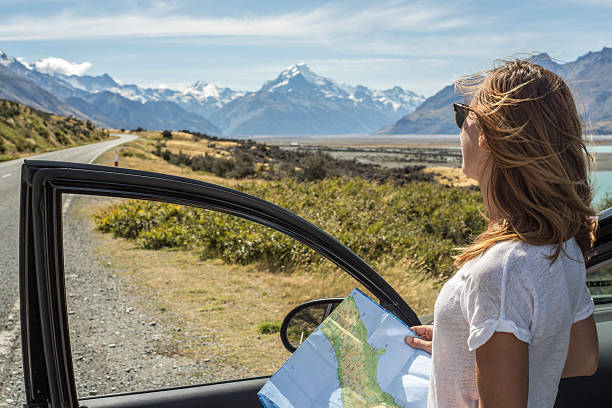 Caucasian standing out of car looking at map, Mount Cook Portrait of a young woman standing out of a car looking at a map for directions. mt cook photos stock pictures, royalty-free photos & images