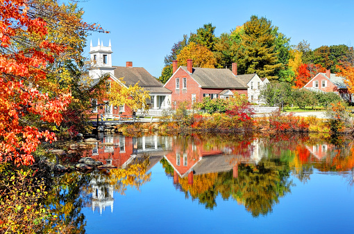 The quaint village of Harrisville New Hampshire reflecting on a small pond in autumn.