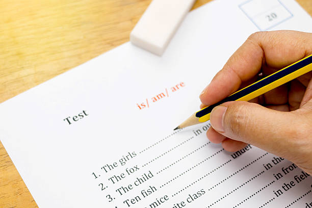 istock hand holding pencil over english test with gradient light 545374188