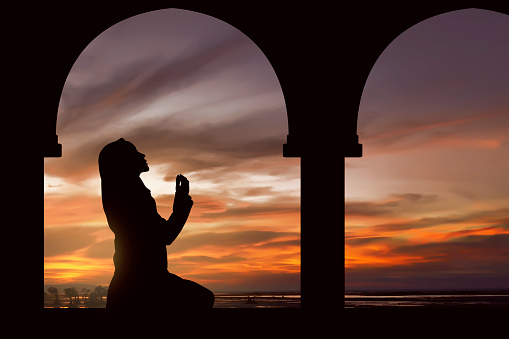 Silhoutte of muslim woman praying during fasting holy month of ramadan