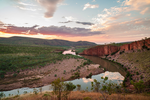 Remote kimberley river system on sunset with red rock cliff face.