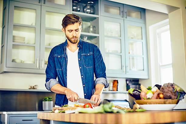 istock Attractive male cutting vegetables at kitchen island 545379314
