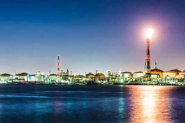 A petroleum refinery facility with flare stack located in a coastal industrial area. 