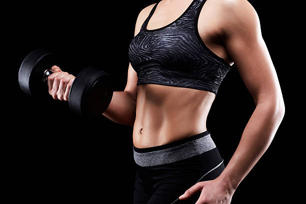 istock Muscular woman exercising with dumbbell showing abs 545424822