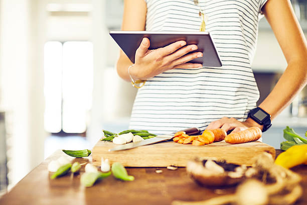 istock Midsection of female holding digital tablet while preparing food 545427658