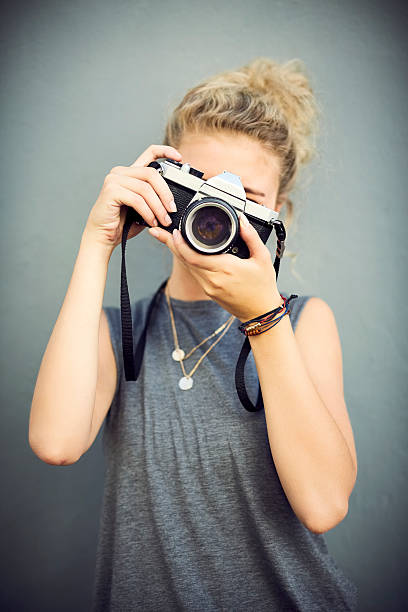 istock Female adjusting camera lens against wall 545428270