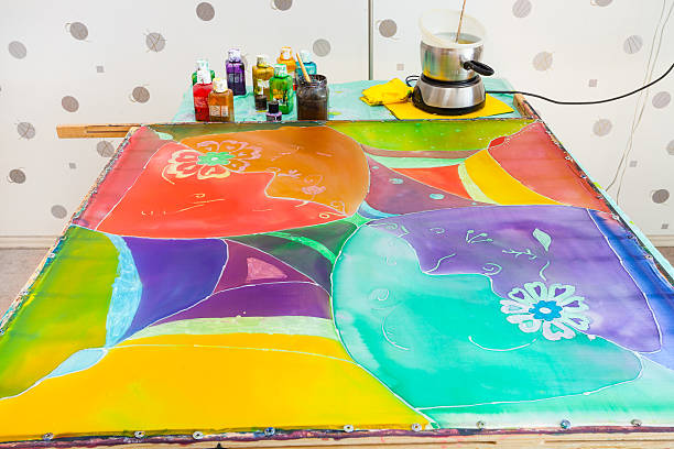 manufacturing steps of hot batik in the workshop - silk canvas with third layer of paints and wax