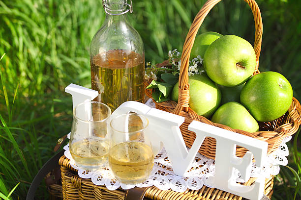 Apple drink and basket with green apples outdoors