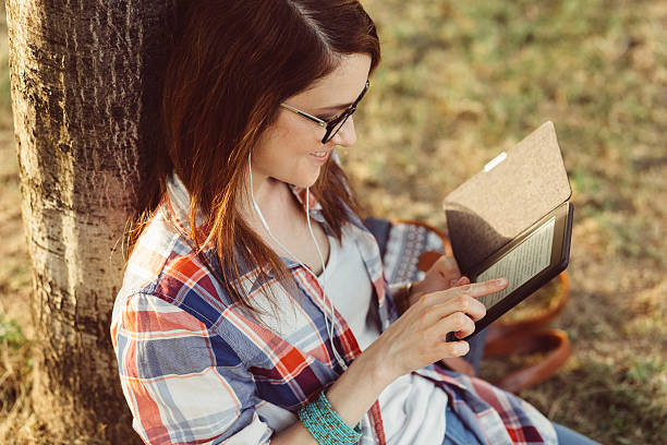 istock Woman among nature reading an e-book 545430822