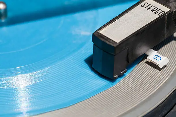 Photo of headshell of old turntable on blue flexi disc